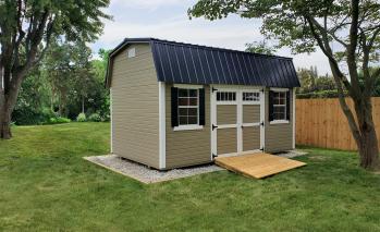Tan Signature High Barn with white trim, double doors, a ramp, windows, and a black roof.